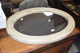 A painted and distressed mahogany bevelled oval wall mirror 79cm x 59cm