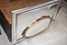 A group of three mirrors, comprising a small oval ornate cast gilt metal mirror, a modern silvered