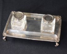 An early George V silver inkstand, of rectangular form having a gadrooned and scroll rim, two silver