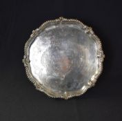 A George V silver salver, of circular form having a gadrooned and scroll rim with personalised