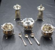A five piece George VI silver condiment set, of bulbous form having Chippendale style rims raised on