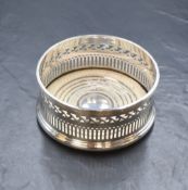 A George V silver wine coaster, of traditional form having a moulded rim and pierced walls on a