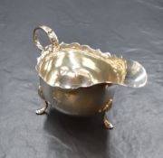 An early George V silver sauce boat, having a Chippendale style rim and generous spout opposed by