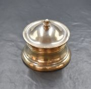 A late Edwardian silver inkwell, of circular form having a hinged lid with moulded finial over a