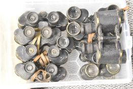 A box containing a quantity of early 20th century binoculars, one having impressed date for 1942..