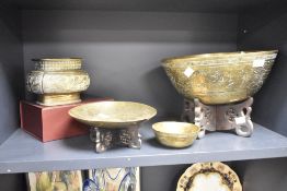 A large brass singing bowl decorated in the Chinese taste, raised on a carved wooden pedestal,