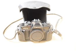 A Canon AV-1 35mm film camera, with Canon branded leather case and strap.