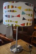 A modern chrome table lamp with reading attachment and fish themed frame