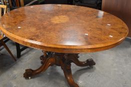 A Victorian walnut loo table having quarter veneered oval top on quadruple turned supported and