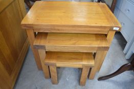 A modern nest of three solid golden oak tables, largest width approx. 65cm