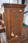 A 19th Century oak corner cupboard of small slender proportions having carved decoration, height