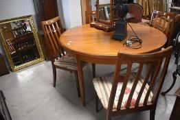 A G plan or similar circular extending dining table and set of similar rail back dining chairs