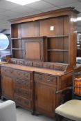 A period oak dresser of breakfront design , having open delft rack with central cupboard , over