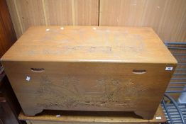 An eastern carved camphor wood blanket box, of traditional design carved with coastal fishing