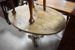A cast iron base pub table with oval oak top, the base with three 'scrolled' legs 71cm x 105cm x