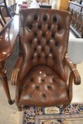 A traditional button back low seat armchair in brown leather
