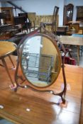 An Edwardian mahogany swing toilet mirror, of oval form pivoted between a shaped surround 73cm