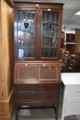 An early 20th Century oak bureau bookcase, the glazed top having leaded glass doors with Art Nouveau