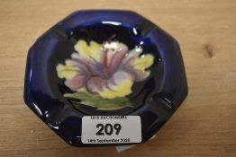 A vintage Moorcroft Hibiscus ashtray in pinks and yellows on a dark blue ground 11cm in diameter