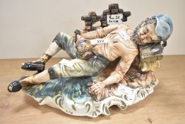 A vintage Capo Di-Monte porcelain figurine depicting a tramp on a bench, markings to underneath.