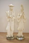Two oriental cast composition figures depicting a male holding a scroll and a female holding a
