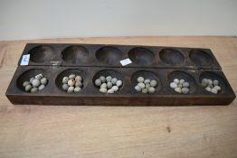 A African/Eastern style figural games board having 12 circular bowls, L51cm