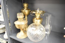 Three brass oil lamps, largest measures 40cm tall, complete with two flutes and a globe.