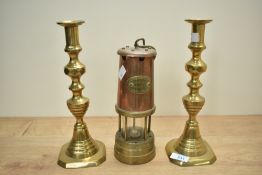 A vintage brass and copper miner's lamp sold together with two brass candlesticks.
