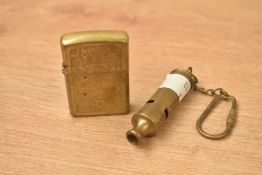 A vintage brass Zippo lighter sold together with a brass whistle.