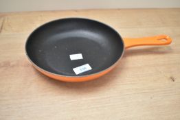 A vintage Le Creuset stainless steel skillet pan, in classic orange colourway, diameter measures