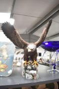 A large resin painted Gold Eagle study perched on a cliff edge, having faded marking to base