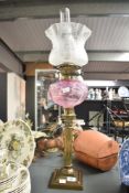 A large Victorian type brass Corinthian column oil lamp having pink vaseline glass reservoir,