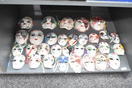 A selection of forty ceramic face masks, varied in size and decoration.