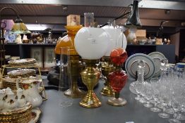 A group of four vintage brass oil lamps, on having a large amber shade etc.