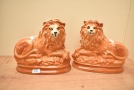 A pair of large Staffordshire pottery lions with inset glass eyes, measure 23cm tall respectively.