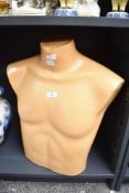 A mid-century shop mannequin of the male torso in thick camel coloured moulded plastic, has