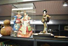A group of three Korean costume dolls, two inside a plastic display cabinet.