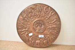 A heavy copper effect plaque depicting the Feast of Bacchus, measures 32cm across.
