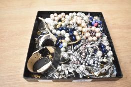 An assortment of costume jewellery, including black and purple pearls, beaded jewellery, brooches