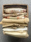 A box of upholstery jacquard in beige and gold tones, with foliate repeat motifs. Various sizes of