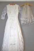 A 1965 wedding dress in snow white Leavers Lace, with starched bow detail and layered skirt, label