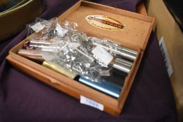 A vintage cigar box containing a selection of guitar slides etc