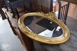 A gilt plaster mirror of oval form, width approx. 80cm