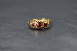 A yellow metal garnet trio ring having three garnets interspersed by two pairs of diamond chips pave