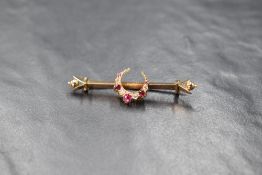 A yellow metal bar brooch stamped 15ct having a central ruby and old cut diamond set crescent,