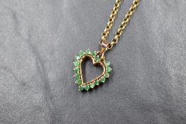 A 9ct gold emerald set open heart pendant, one stone missing, on a 9ct gold 18' belcher link