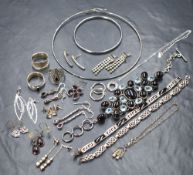An assortment of silver jewellery, including hoop earrings, garnet set drop earrings, rings and