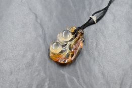 A Chinese carved agate pendant depicting a bird with two lotus fruits having a cord loop with