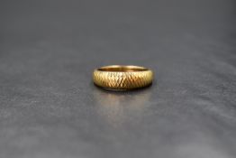 An 18ct gold band, the graduated band having a decorative textured design, marked 750 18K, ring size