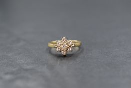 A 9ct gold diamond set cluster ring, the central round brilliant cut diamond measuring approximately